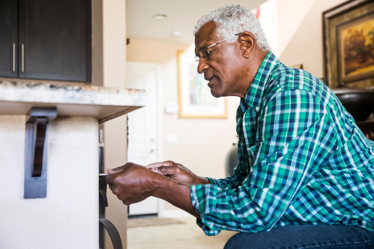 senior male doing maintenance on a home with a screwdriver